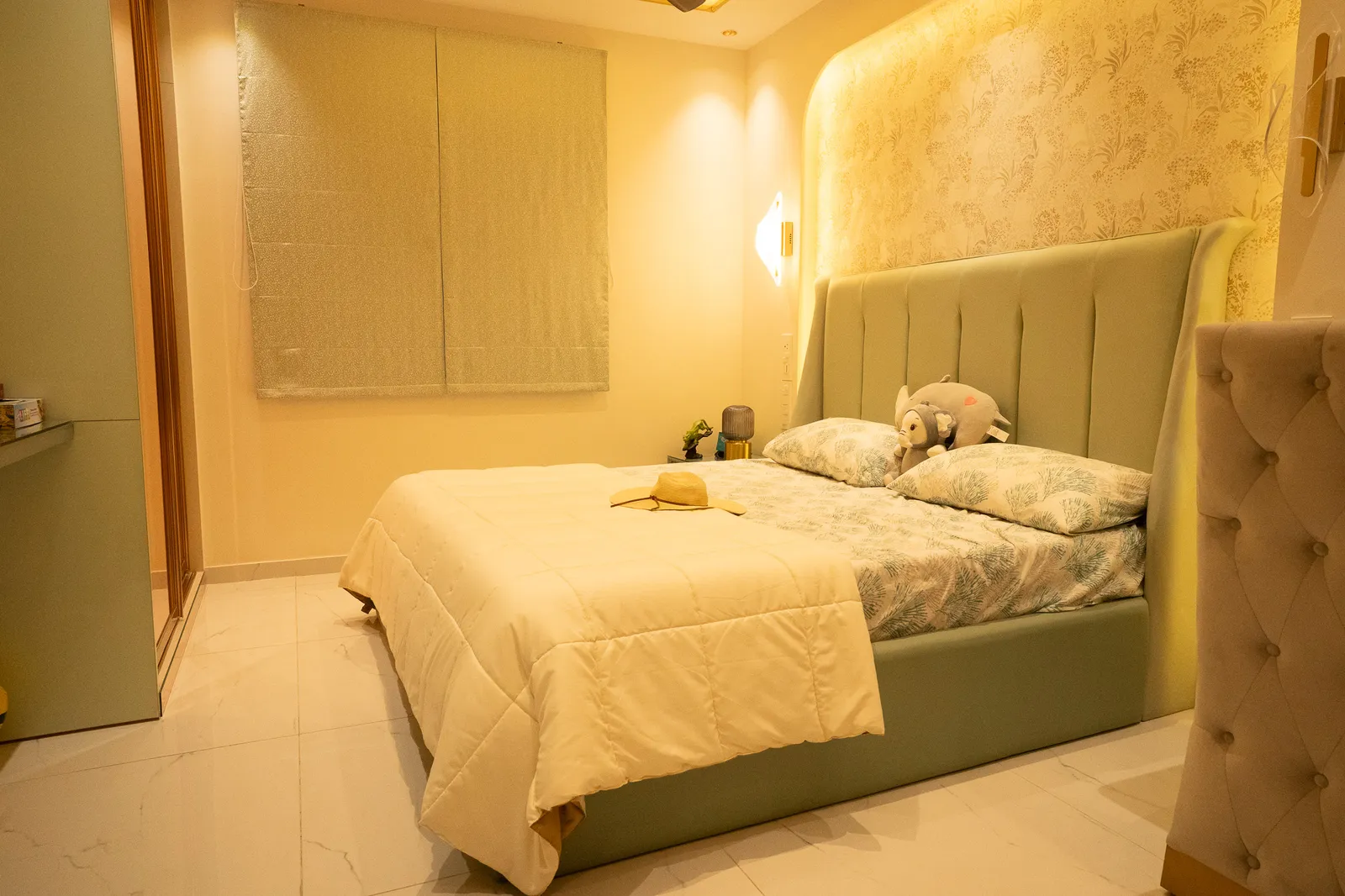 Bedroom with sage upholstered headboard and arched backlit niche — Divyarjuna